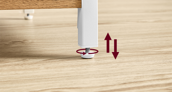 avec base circulaire rouge sur plancher en bois. Les flèches indiquent la capacité de réglage vertical. Pied blanc visible au-dessus du dispositif de réglage.