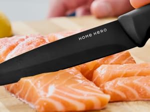avec la marque « Home Hero » pour trancher du saumon cru sur une planche à découper en bois. Couteau tenant une main visible à l'arrière-plan.