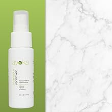 Flacon pulvérisateur blanc avec des accents verts sur fond marbré. Le produit semble être une solution de soin de la peau ou des cheveux