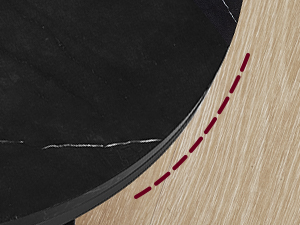 Gros plan d'un bord incurvé noir avec des coutures rouges, contrastant avec une surface en bois clair