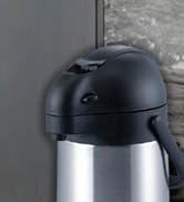 Gros plan d'une carafe isotherme ou d'un airpot en acier inoxydable et noir. Le dessus est doté d'un couvercle en plastique noir avec un mécanisme de versement.