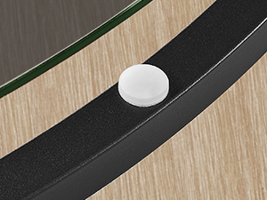 Deux bandes noires parallèles montées sur une surface en bois clair avec un petit objet circulaire blanc entre elles.