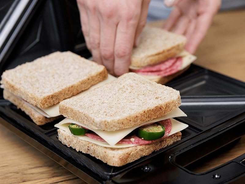 Séquence étape par étape montrant des mains assemblant un sandwich sur ce qui semble être une surface ou une plaque chauffante de couleur foncée.