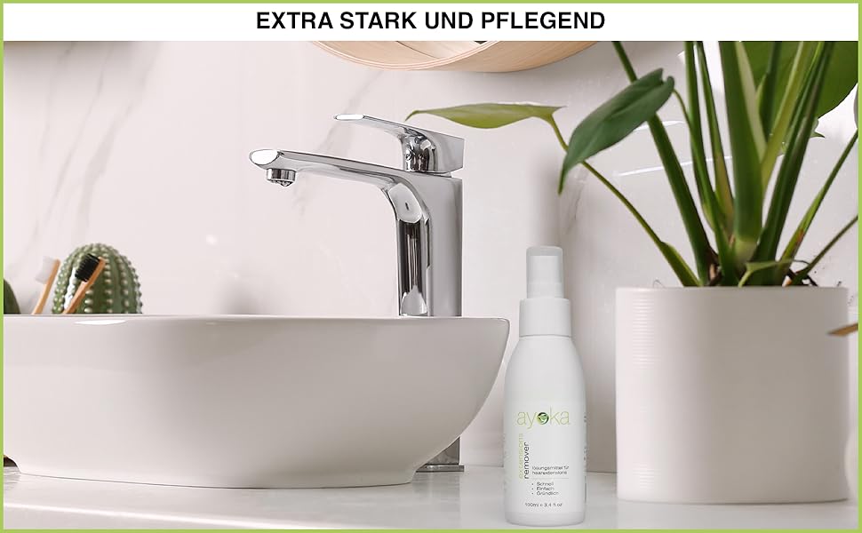 avec robinet élégant. Vasque blanche sur le plan de travail. Plantes en pot et bouteille de toilette visibles