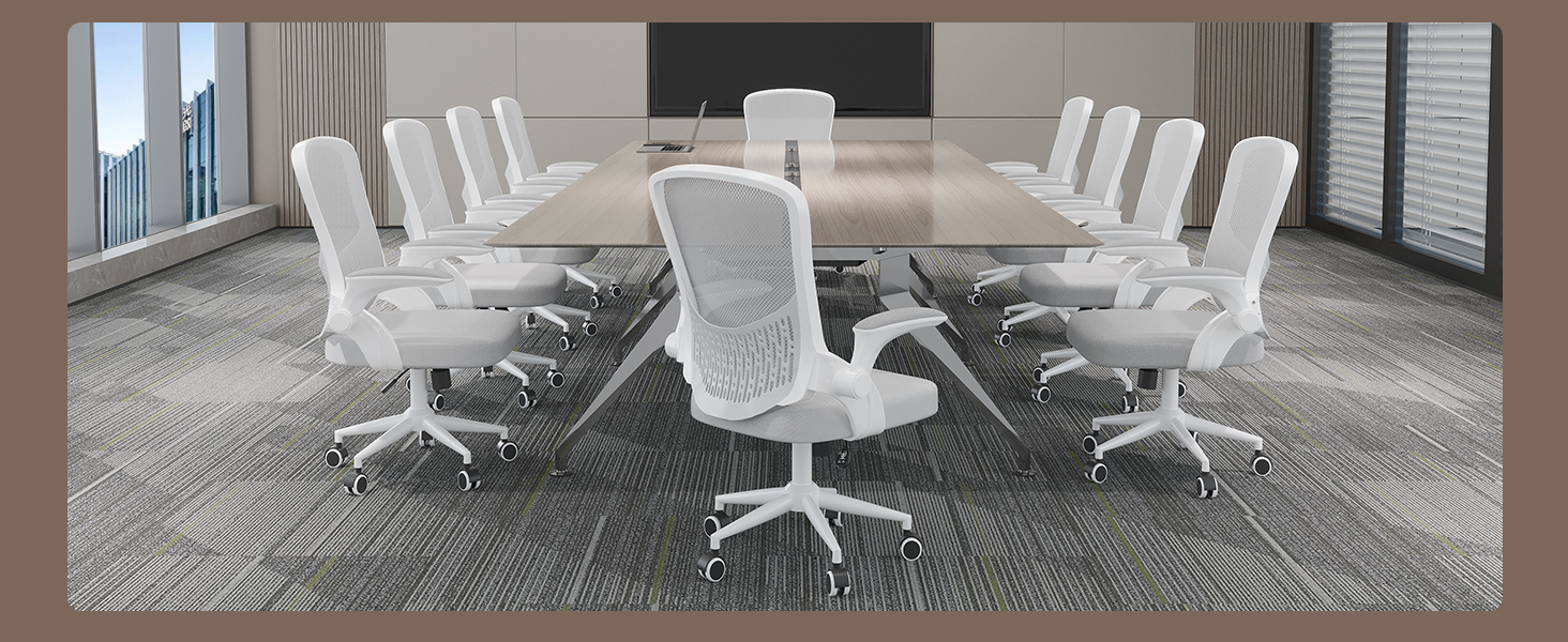 Salle de conférence moderne avec une grande table ovale et plusieurs chaises de bureau en maille blanche, adossées à un tapis à motifs et à un mur vitré.