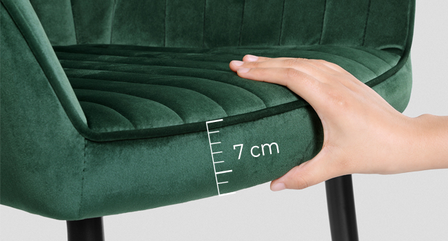 en velours vert avec assise capitonnée. Main démontrant l'épaisseur du coussin de siège de 7 cm à l'aide d'une échelle de mesure.