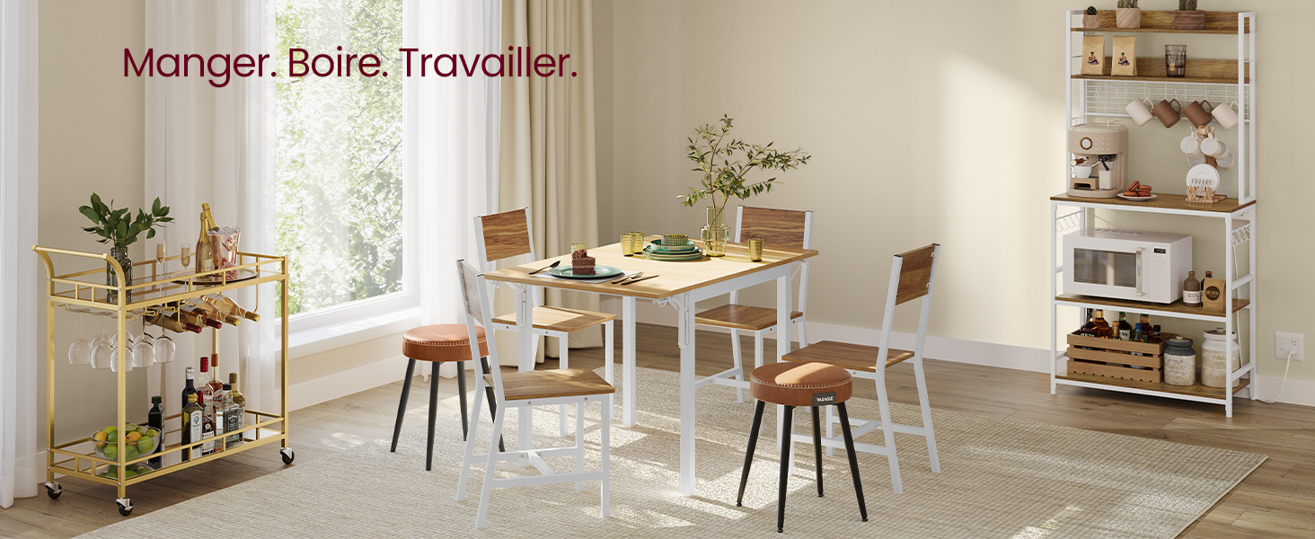 Espace à manger moderne avec table blanche, chaises en bois, chariot à barres doré et étagère. Le texte se lit comme suit : « Manger. Boire. Travailler. »