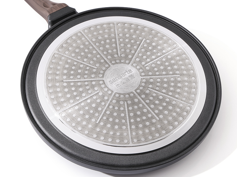 Gros plan d'une grande poêle ou plaque chauffante circulaire dotée d'une surface antiadhésive texturée et d'un bord extérieur foncé, mettant en valeur le design de sa surface