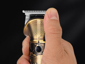 Gros plan d'une tondeuse à cheveux électrique dorée ou d'une tondeuse à cheveux tenue à la main, avec lame visible