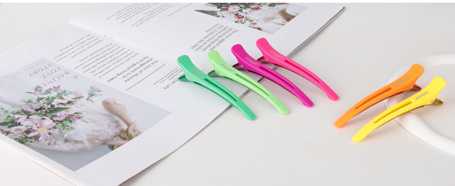 Pinces à cheveux en plastique colorées en vert, rose, orange et jaune affichées sur un livre ouvert ou une page de magazine.