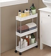 Chariot roulant étroit à trois niveaux en blanc, placé à côté d'une armoire. Les étagères contiennent des produits de salle de bain et des serviettes.