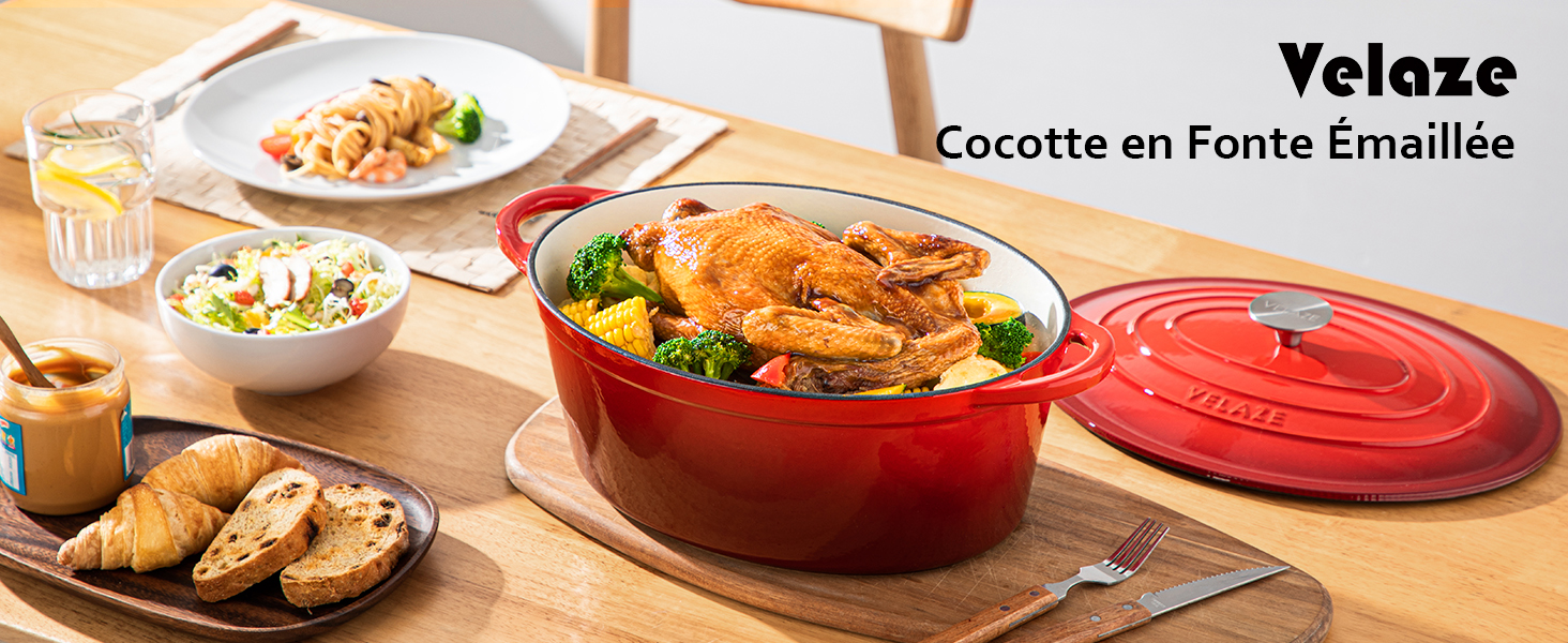 Cocotte en fonte émaillée rouge de Velaze, représentée sur une table avec du poulet rôti et des légumes. Couvercle et autres plats visibles sur la scène.
