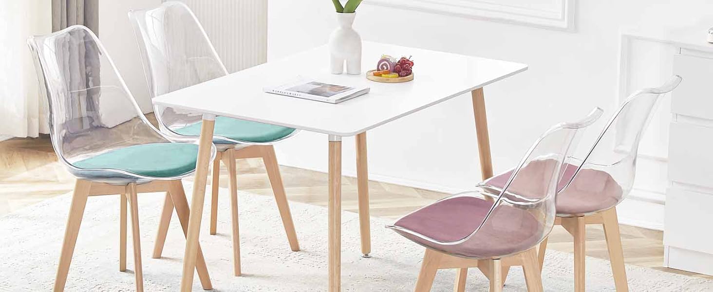 avec table blanche et quatre chaises. Les chaises ont des pieds en bois et des sièges colorés en clair, bleu et rose.