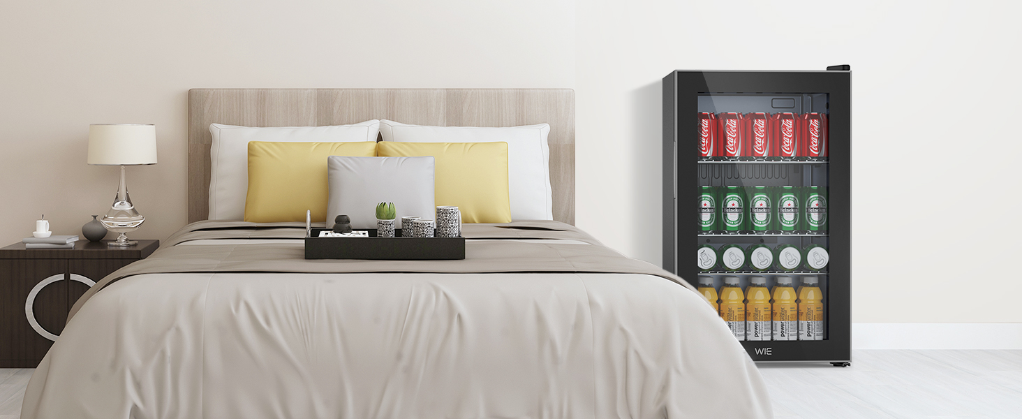 Chambre moderne avec un lit king-size et un petit réfrigérateur à boissons. Le réfrigérateur est doté d'une porte vitrée proposant diverses boissons et collations.