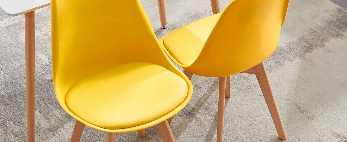 avec table blanche et deux chaises jaune vif. Pieds de chaise en bois. Set de table avec assiettes et objets de décoration.