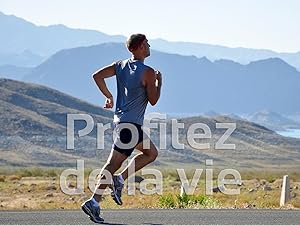 Homme en chemise bleue faisant du jogging sur un chemin avec un paysage montagneux en arrière-plan. Le texte superposé indique « Profitez de la vie » (en français pour «