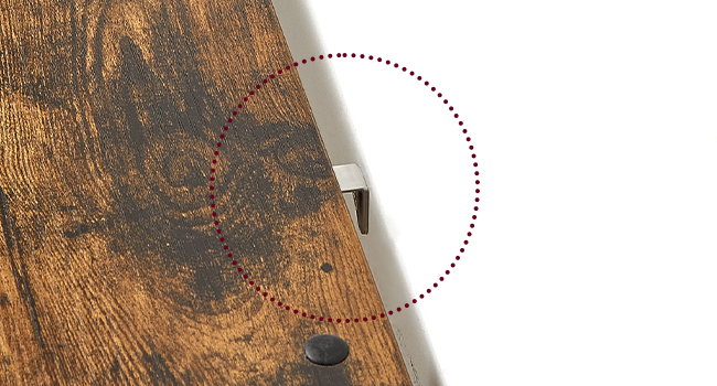 Gros plan d'une surface en bois avec un nœud foncé ou une imperfection entourée d'une ligne pointillée rouge. Bordure métallique visible sur le côté droit.