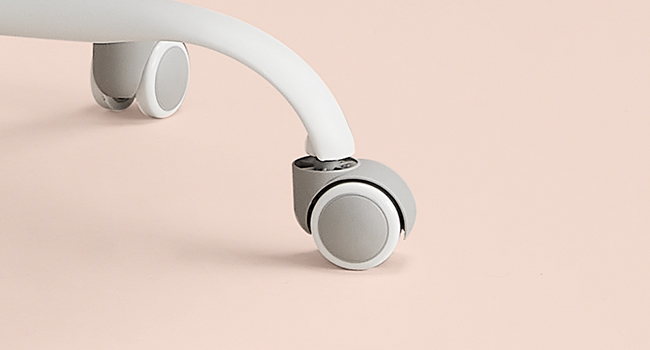 Gros plan de roulettes blanches sur une surface rose pâle, probablement pour la mobilité du mobilier ou de l'équipement