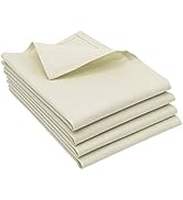 Pile de serviettes pliées en coton de couleur crème. Quatre serviettes sont soigneusement empilées, dont une partiellement dépliée pour montrer la texture et l'épaisseur