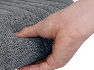 Gros plan d'une main appuyant sur la surface d'un tissu texturé gris, démontrant le rembourrage ou la douceur du