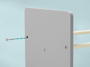 Plaque ou support de montage blanc contre un mur bleu clair, avec trous de montage et quincaillerie visibles.