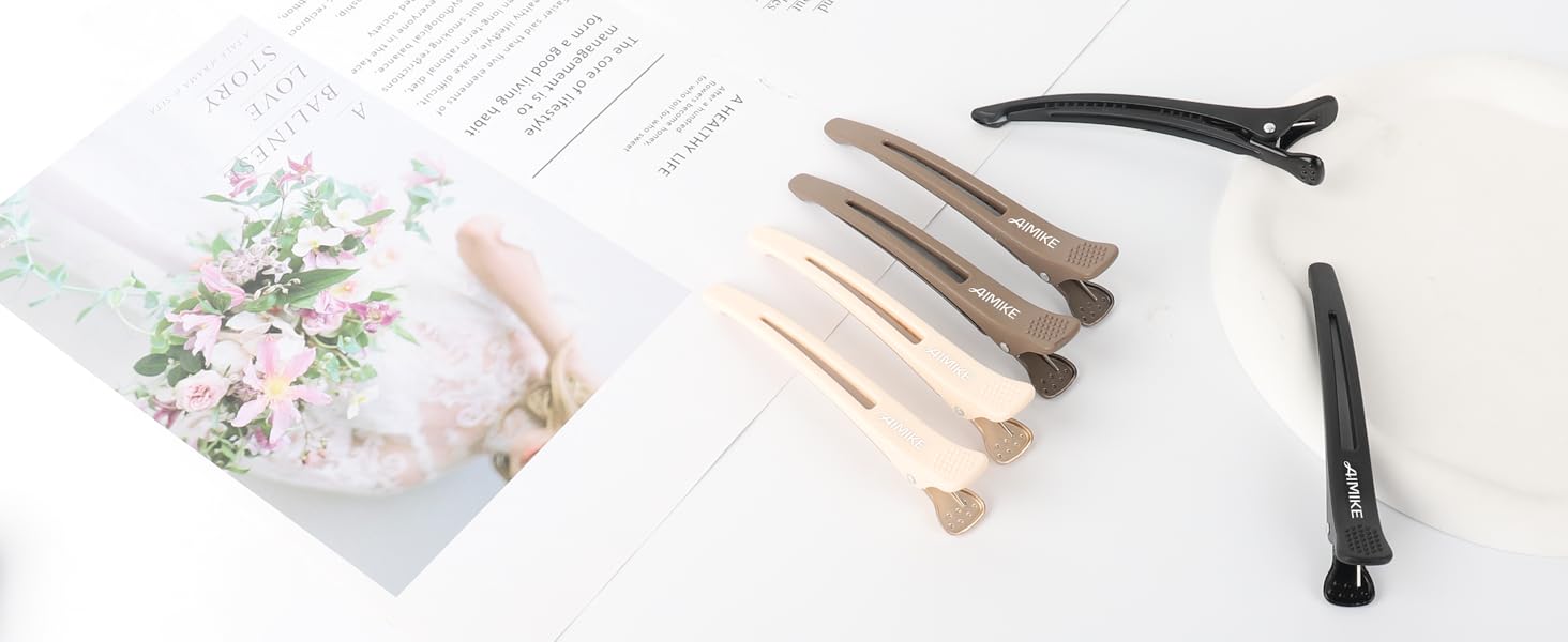 Collection de pinces à cheveux dans différents tons neutres, y compris le beige, le marron et le noir, affichées sur une surface blanche à côté d'un imprimé floral.