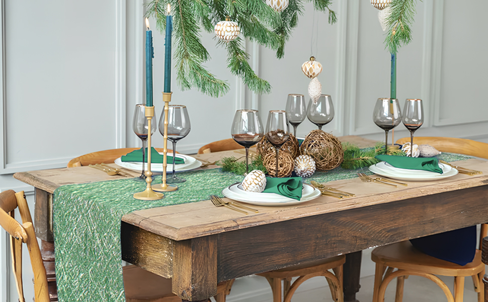Décoration de table de fête avec table en bois, chemin de table vert, verres à vin et décorations de branches de pin avec ornements et pommes de pin