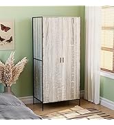 Armoire de rangement blanche présentée dans le décor de la pièce avec des murs et une fenêtre verts, décorée avec des objets décoratifs sur le dessus, notamment des fleurs séchées.