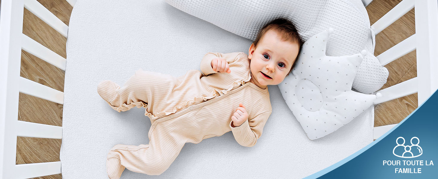 un bébé allongé sur un lit blanc.