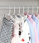 Rangée de vêtements suspendus sur des cintres blancs avec des chemises à carreaux, unies et à motifs pastels et imprimés