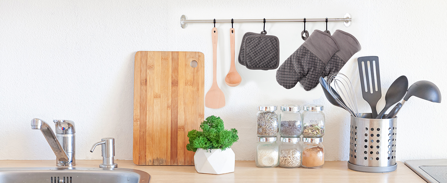 avec ustensiles, planche à découper, herbes en pot et contenants de rangement. Les ustensiles sont suspendus à un rail au-dessus.