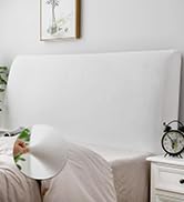 Gros plan de la tête de lit rembourrée gris clair dans la chambre à coucher avec une literie blanche et