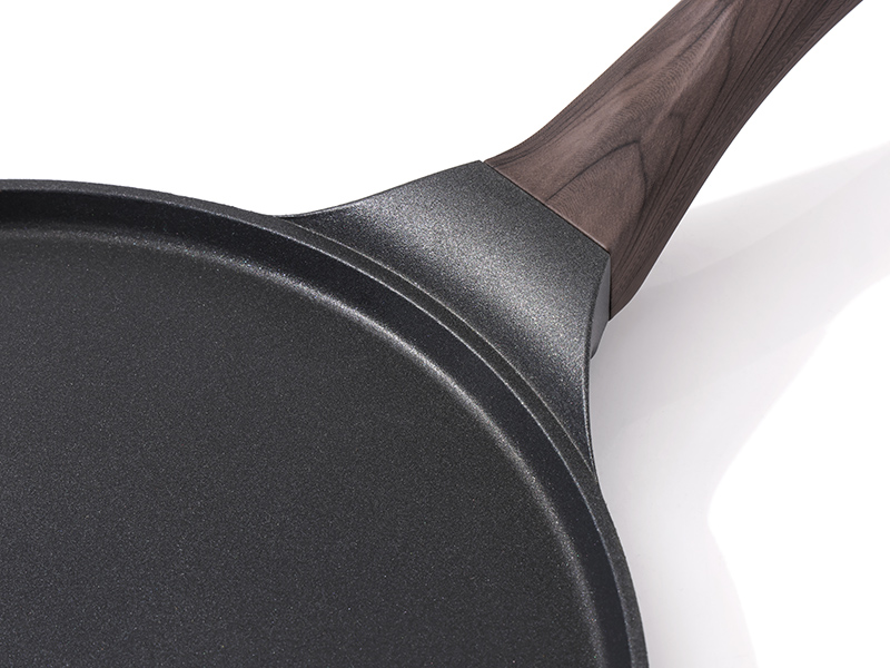 Vue rapprochée du manche et du bord d'une poêle antiadhésive, montrant une surface texturée gris foncé