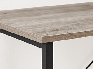 Gros plan d'un coin de table montrant un plateau en bois clair avec un cadre en métal noir en dessous, soulignant l'intersection des matériaux et du design