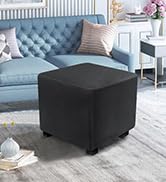 Pouf ou pouf carré noir dans un salon avec un canapé capitonné gris visible en arrière-plan