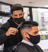 Coiffeur professionnel donnant une coupe de cheveux, démontrant une technique de coupe précise sur les cheveux du client à l'aide de ciseaux et d'un peigne professionnels.