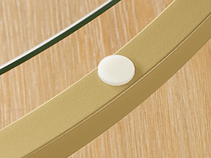 Gros plan d'un objet blanc circulaire sur une surface en bois avec des éléments incurvés en métal ou en verre à proximité