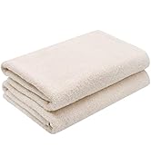 Deux serviettes de bain pliées de couleur crème empilées les unes sur les autres. Les serviettes semblent moelleuses et fabriquées dans un matériau doux et absorbant