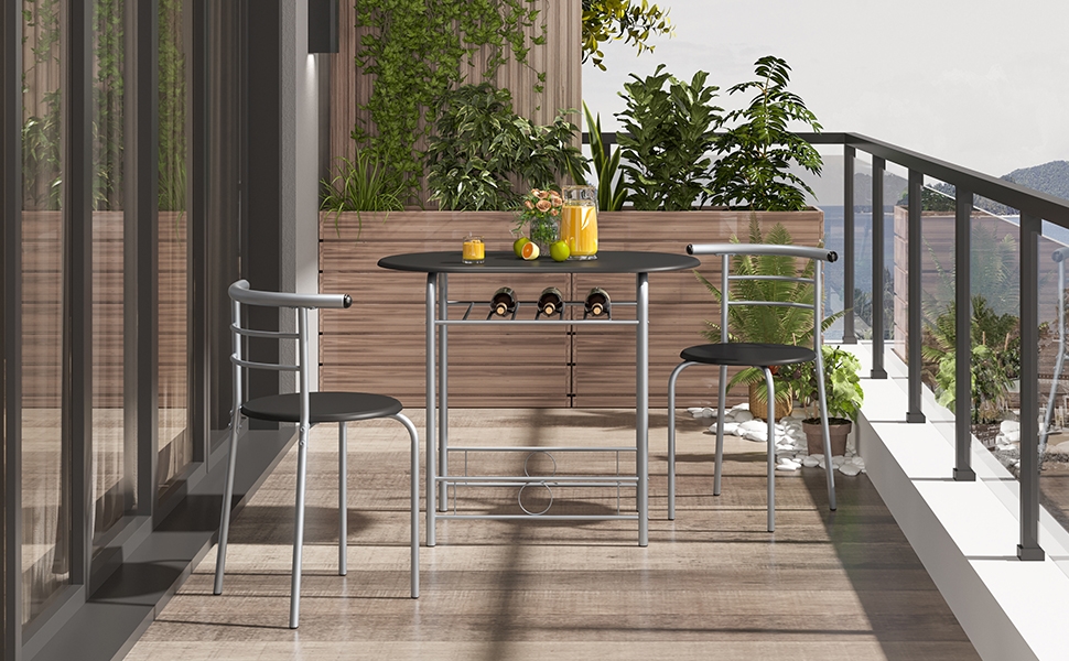 Balconnet extérieur avec parquet, avec une petite table ronde et deux chaises. Des plantes et une balustrade sont visibles en arrière-plan.