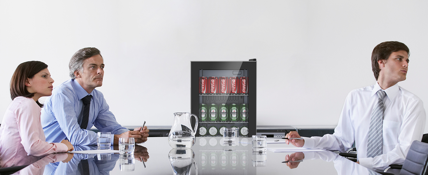 Scène de réunion de bureau avec des personnes assises à une table. Un refroidisseur de boissons avec des bouteilles rouges et vertes est visible à l'arrière-plan.