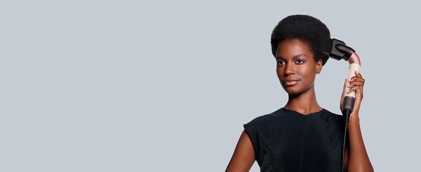 Le Dyson Supersonic r et le peigne à dents larges utilisés par un mannequin pour étirer les cheveux.