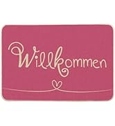 Paillasson rose ou panneau de bienvenue avec un texte cursif doré sur lequel on peut lire « Willkommen » et un petit cœur.