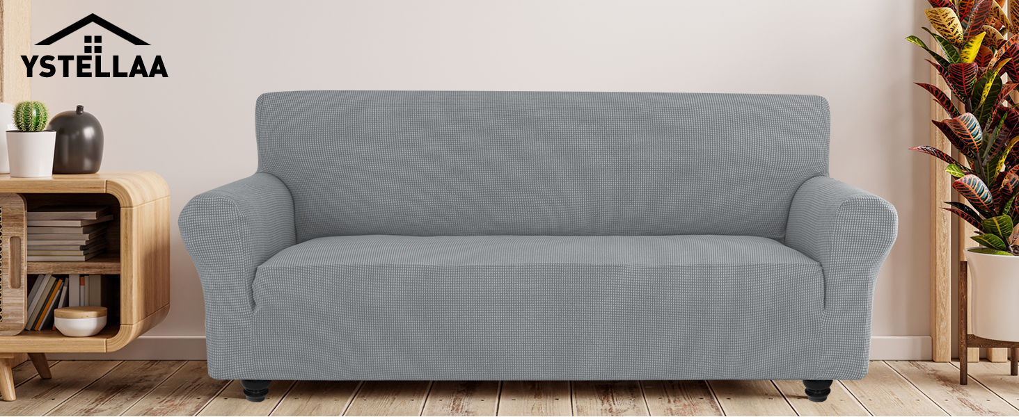 texturé gris à motif ondulé, positionné contre un mur de couleur claire. Table d'appoint en bois et plantes en pot visibles.