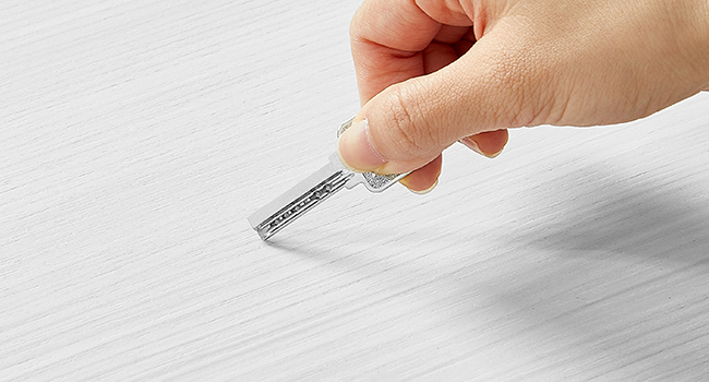 Gros plan d'une main tenant une petite bande de plastique transparent avec des marques, probablement à des fins de mesure ou de test.