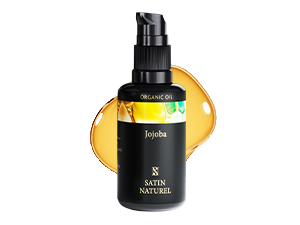 Flacon noir avec distributeur à pompe contenant de l'huile de jojoba. Liquide jaune visible à travers la partie transparente du flacon. Le produit semble être destiné aux soins de la peau ou à des fins cosmétiques.