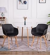 comprenant deux fauteuils noirs avec pieds en bois, une table ronde blanche et un décor minimaliste comprenant un vase et des œuvres d'art mural
