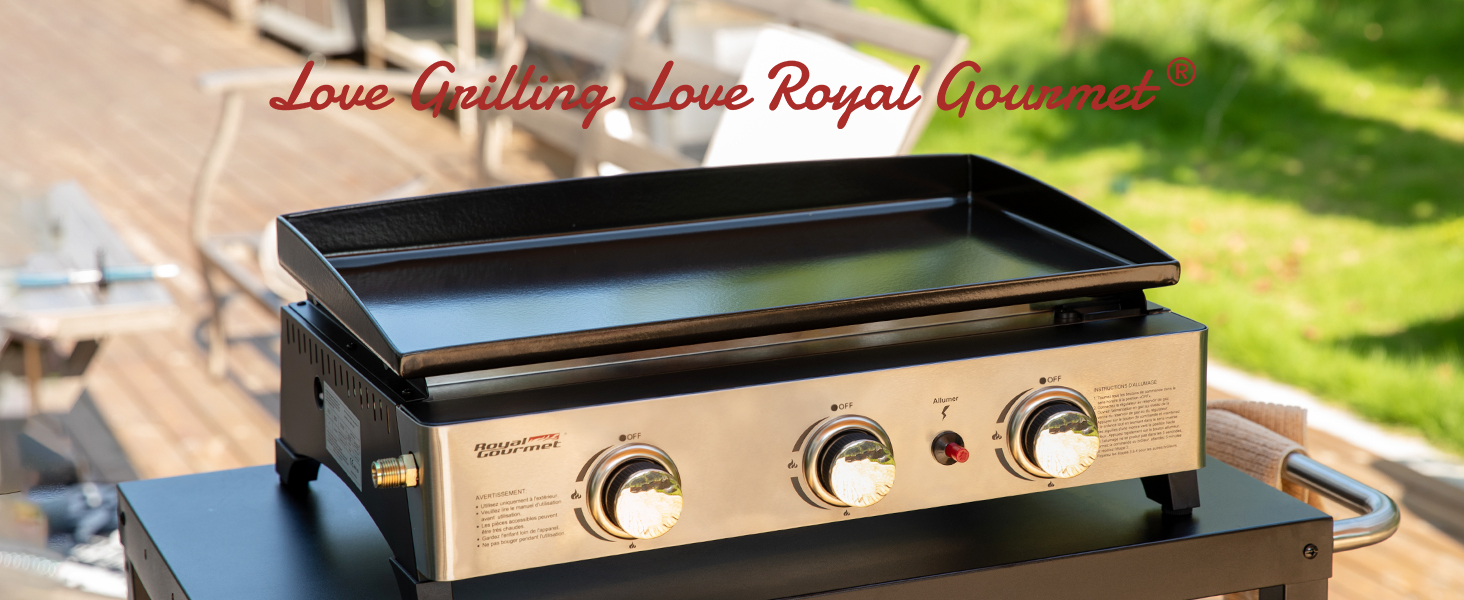 avec trois boutons de commande. Design en acier inoxydable et noir, grande surface de cuisson visible. Situé sur une terrasse en bois dans un jardin.