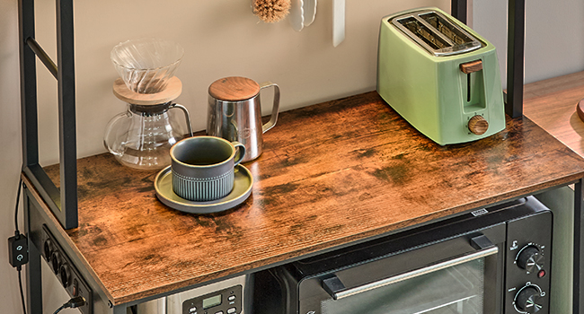 Intérieur de cuisine moderne avec plans de travail en bois, montrant de la vaisselle empilée et de petits appareils électroménagers dans un cadre lumineux et minimaliste avec des murs blancs et un éclairage naturel.