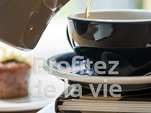 Le café est versé dans un ensemble de tasses et de soucoupes en céramique noire. La tasse est placée au-dessus de livres ou de magazines empilés.