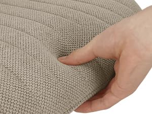 Gros plan d'une main appuyant sur la surface d'un tissu texturé beige pour démontrer sa douceur ou sa flexibilité